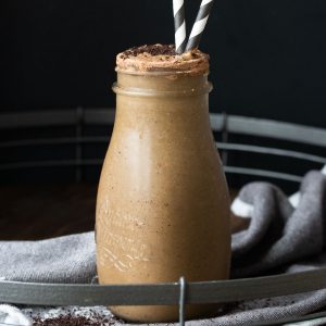 Coffee smoothie in a glass milk jar with two straws.
