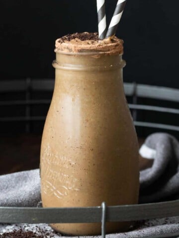 Coffee smoothie in a glass milk jar with two straws.