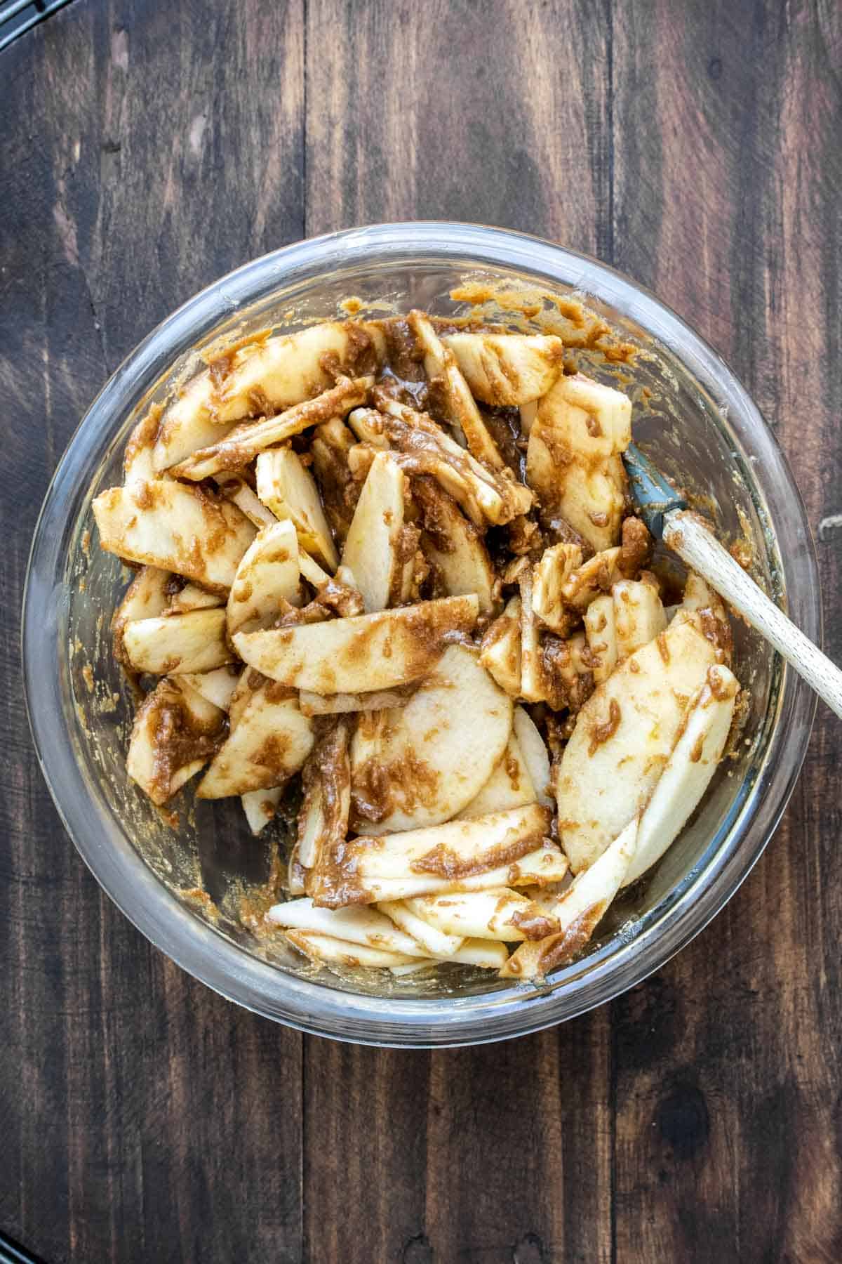 Sliced apples covered in brown topping in a glass bowl