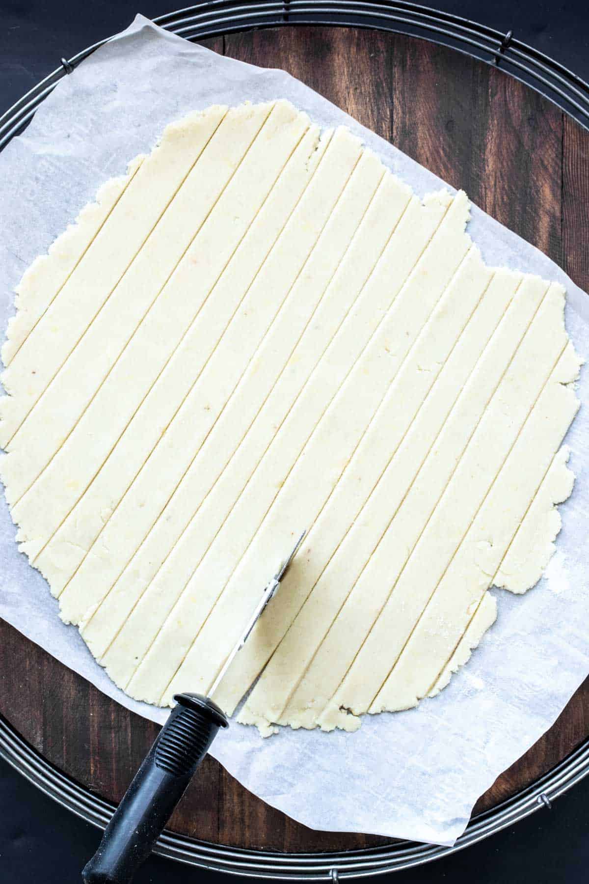 A pizza cutter cutting strips of pie dough