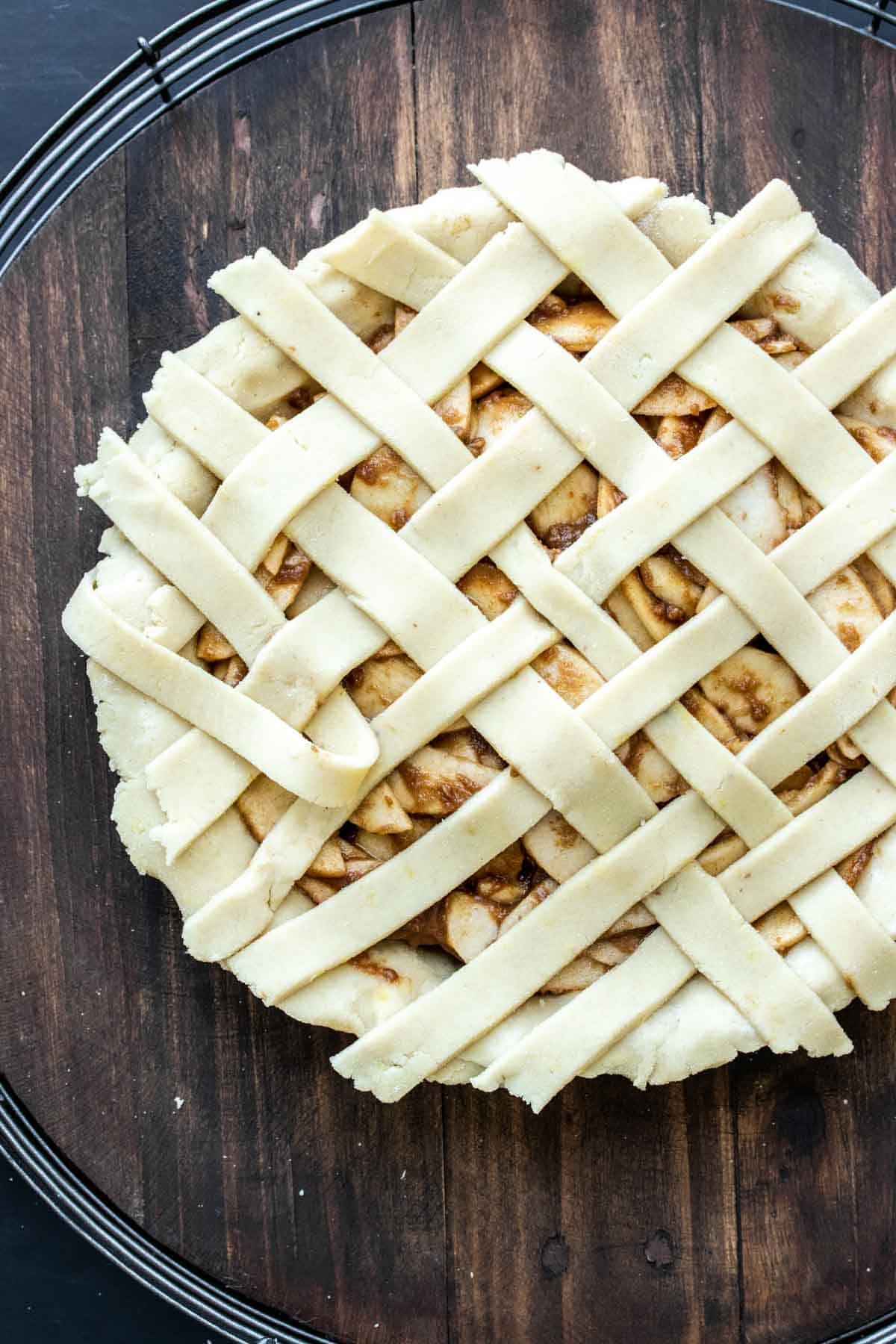 A raw apple pie with strips of pie dough being woven