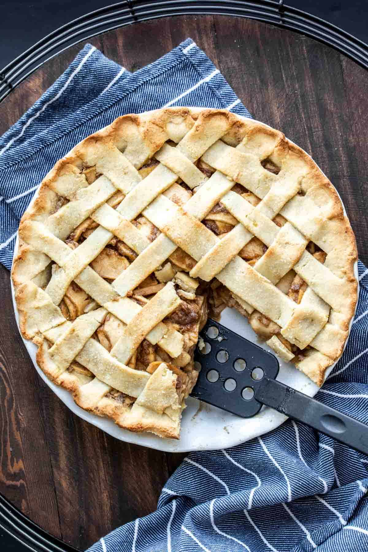 A spatula taking out a piece of apple pie from a pie dish