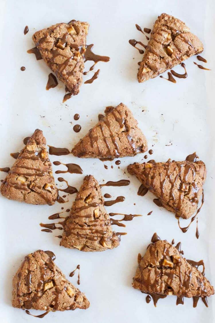 Eight triangle apple scones with glaze on parchment paper