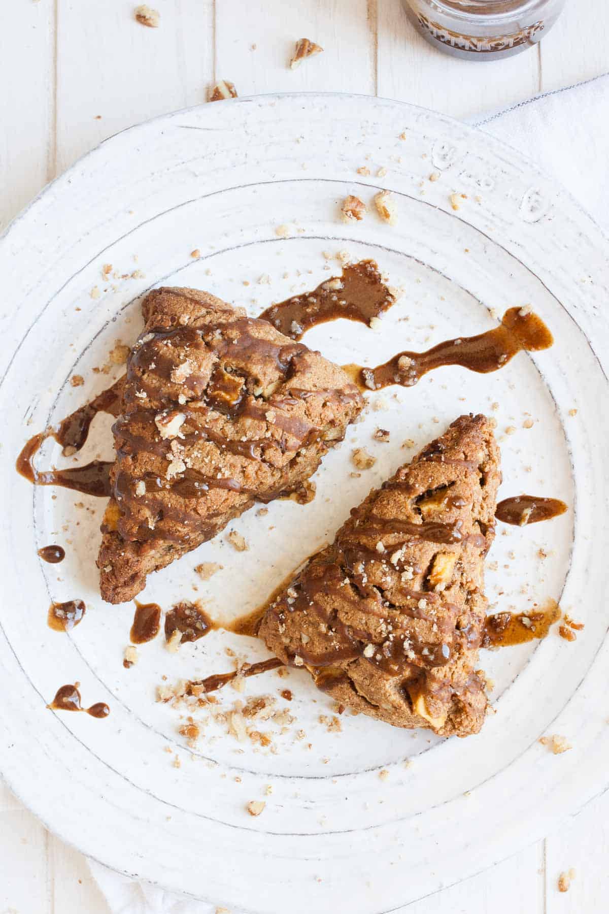 Two triangle shaped apple scones on a white plate with glaze drizzle