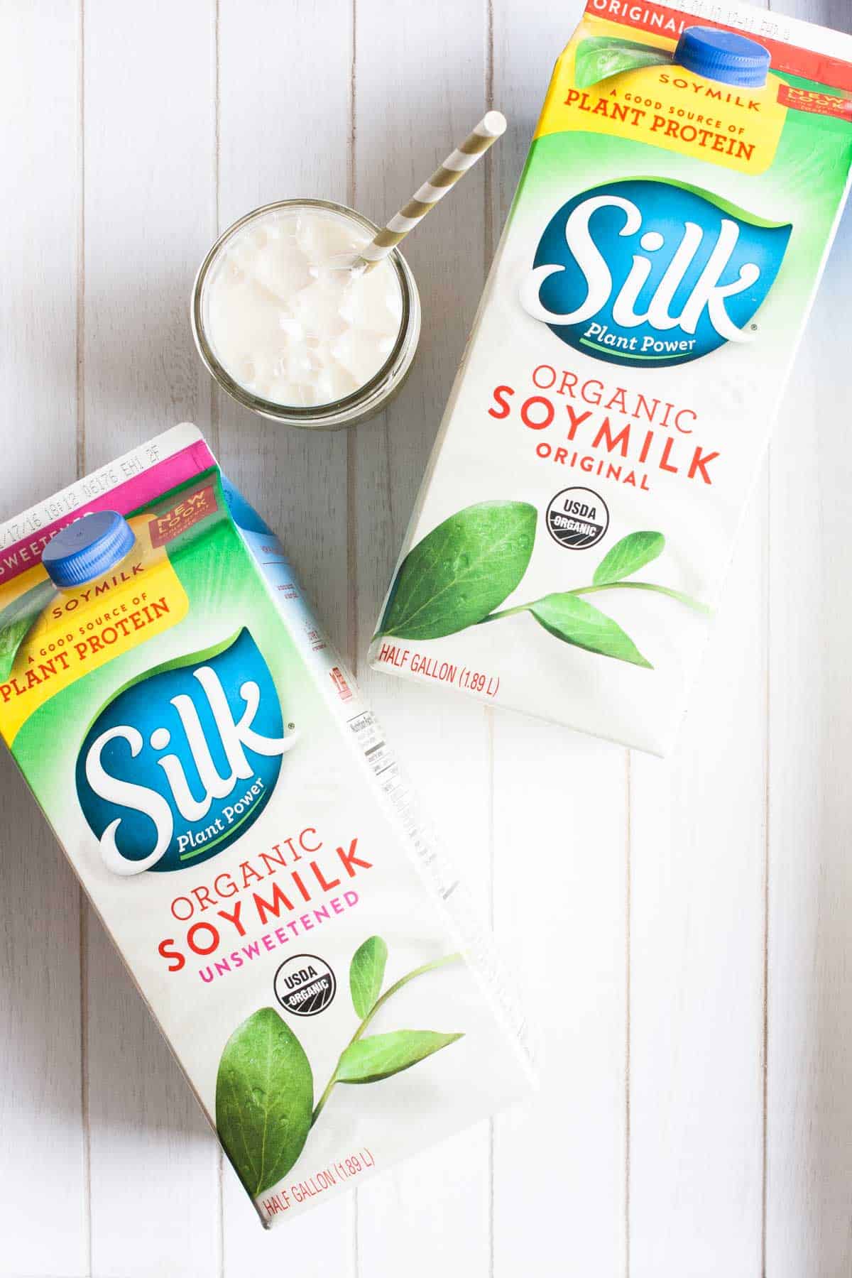 Two cartons of silk brand soy milk laying on a white wood table