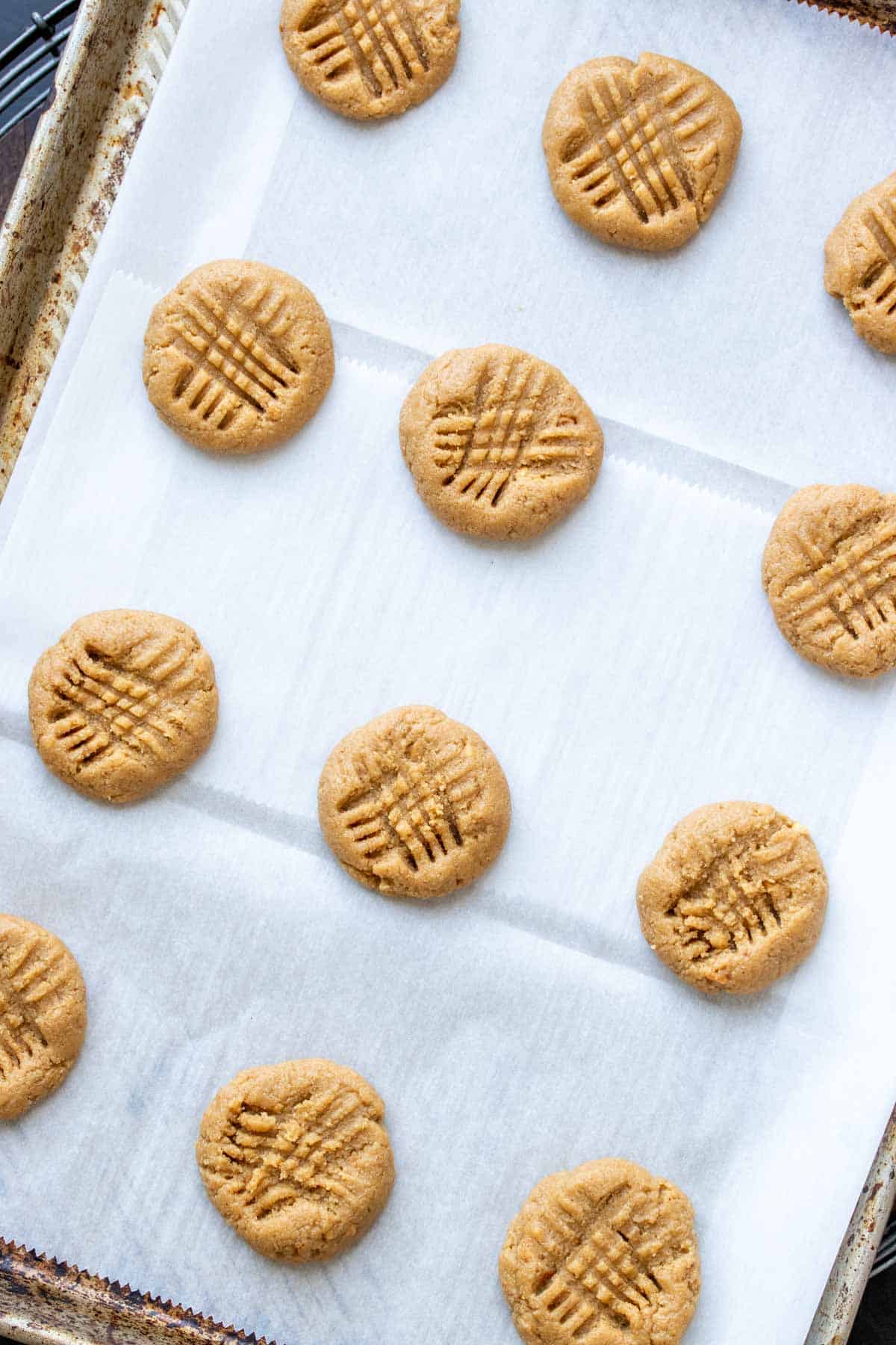 Raw peanut butter cookies on a parchment lined baking sheet