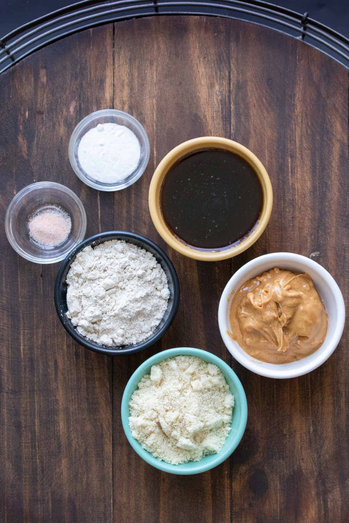 Different colored bowls with ingredients for peanut butter cookies