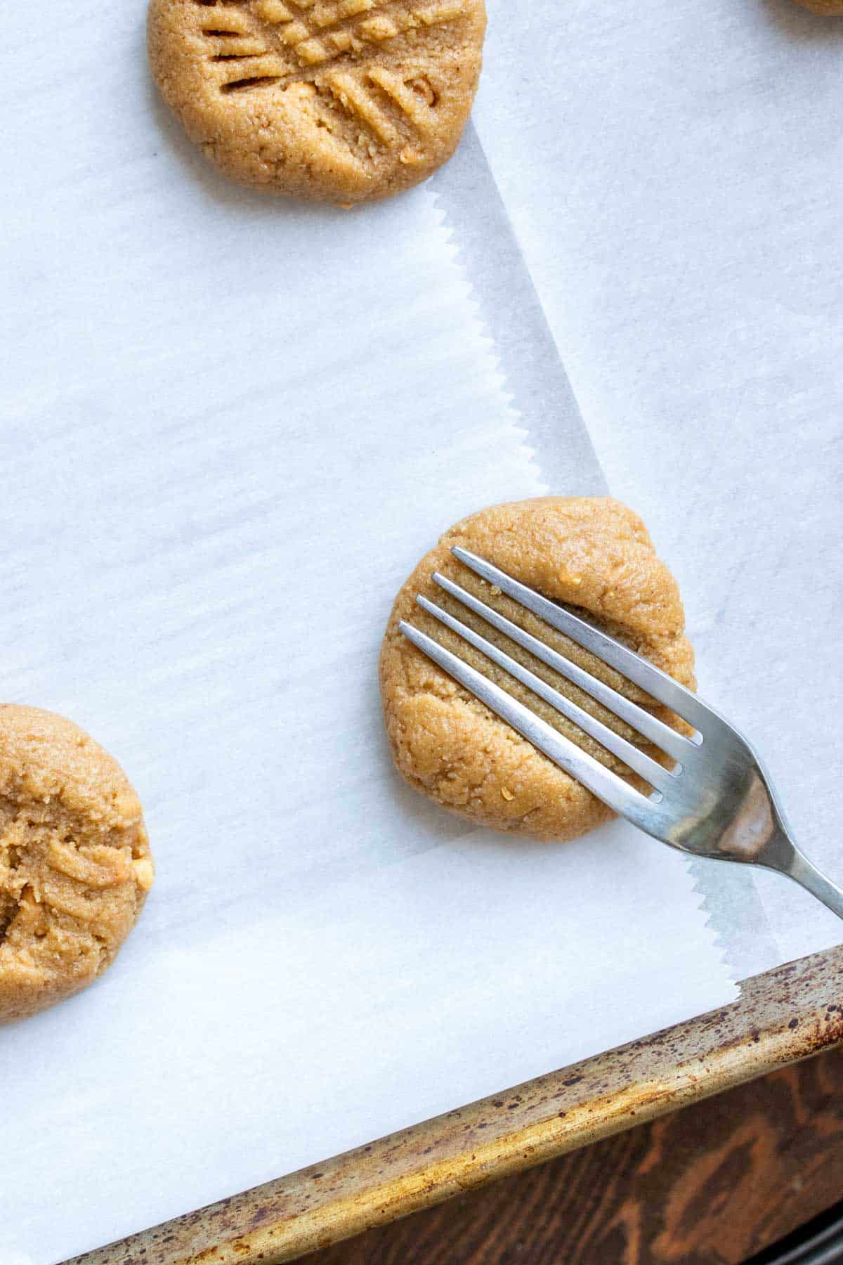 Fork pressing down on a ball of peanut butter cookie dough