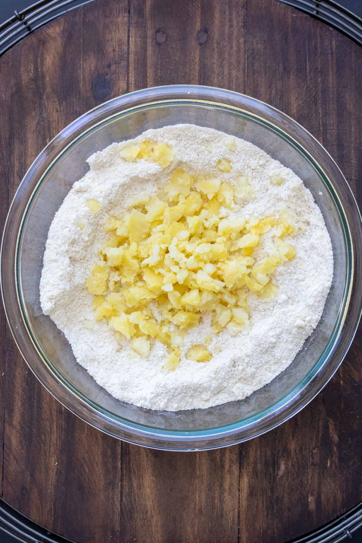 Glass bowl with flour and crumbled cooked potato