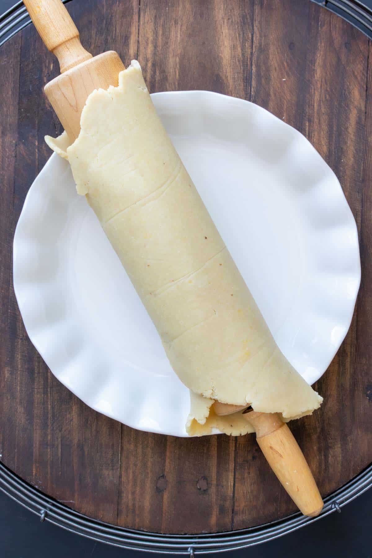 Pie dough rolled around a rolling pin and on the pie dish