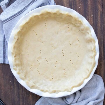Top view of pie dough molded into a pie dish with scalloped edges