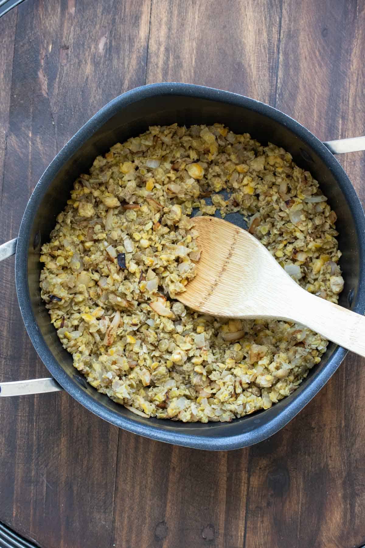 Wooden spoon mixing chopped beans in a pot