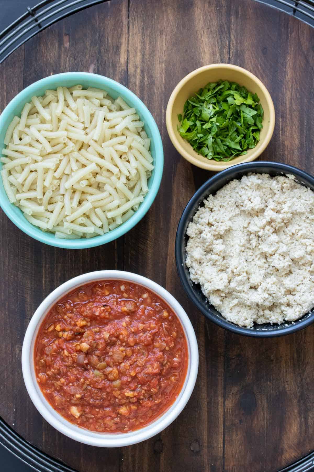 Bowls with ingredients to make a baked pasta and sauce dish