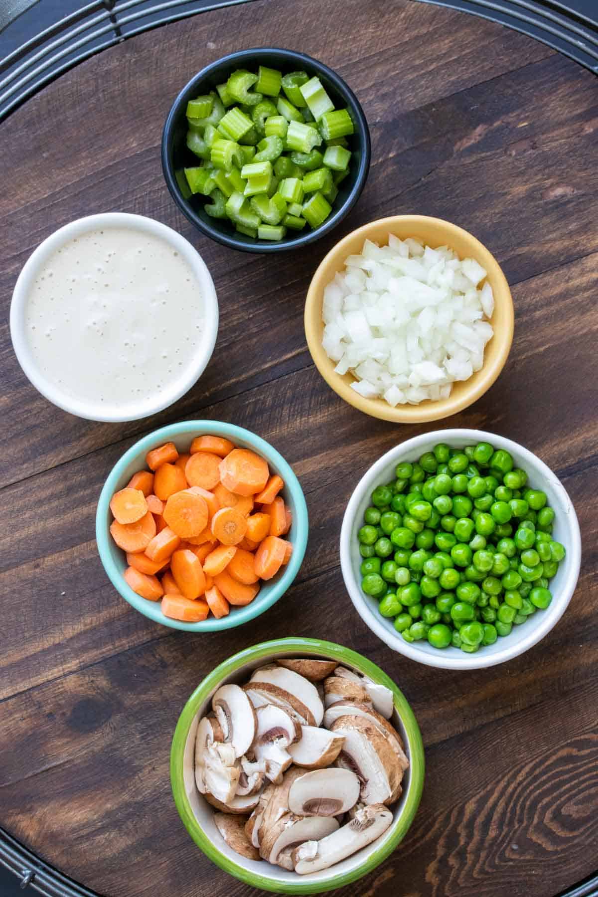 Different colored bowls filled with veggies on a wooden surface