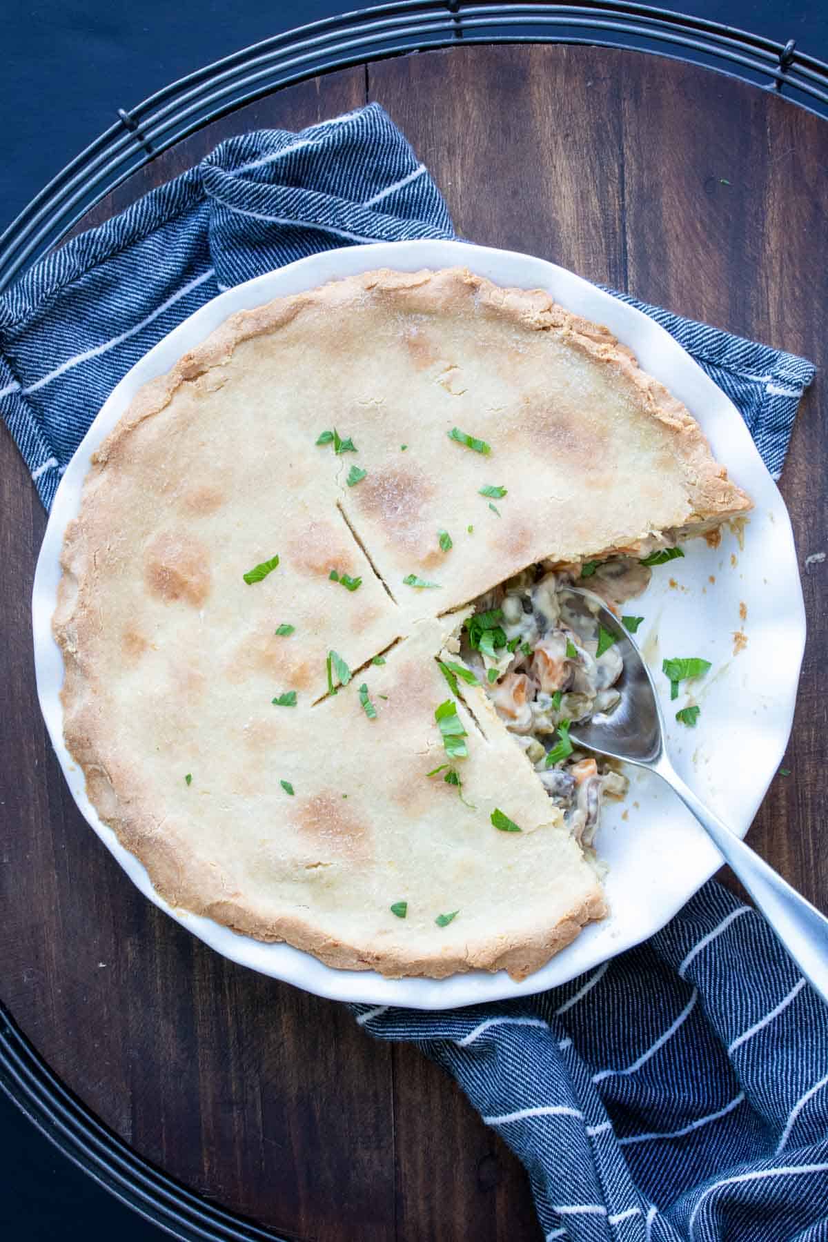 A spoon scooping out vegetable pot pie from a pie dish.