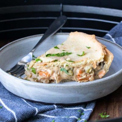 A piece of veggie pot pie on a plate with a fork next to it