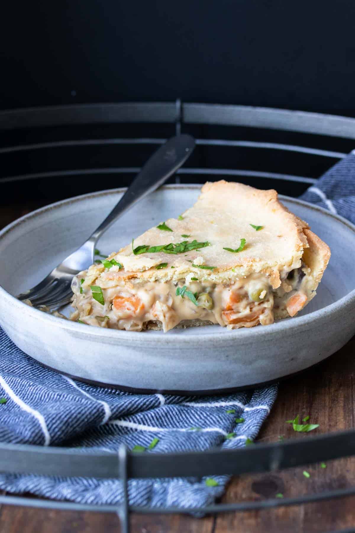 A piece of veggie pot pie on a plate with a fork next to it