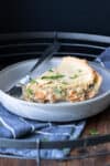 A piece of vegetable pot pie on a grey plate with a fork next to it.