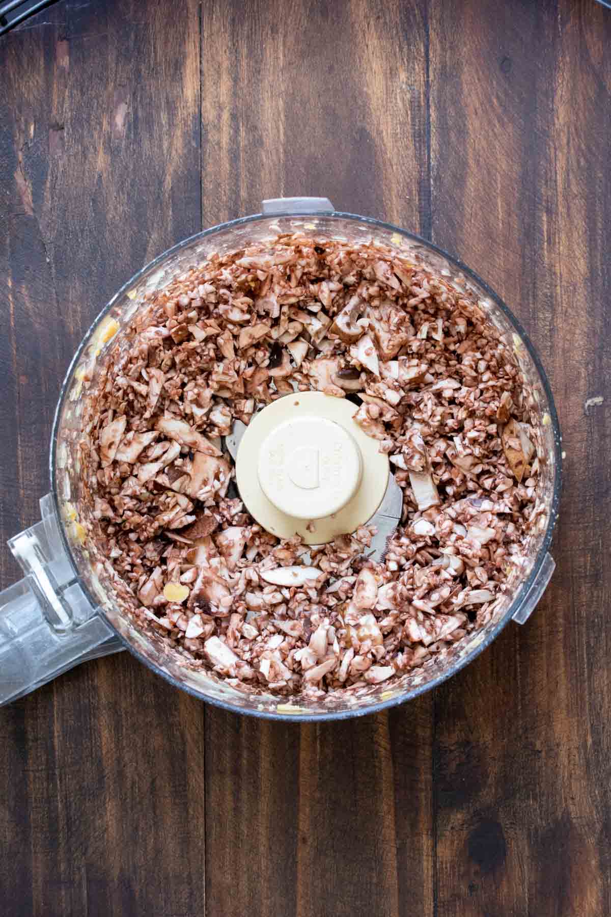 Top view of food processor with chopped mushrooms