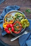 Quinoa stuffed peppers on a grey plate with their tops on the side