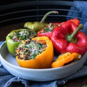 Grey plate with tri colored quinoa stuffed peppers