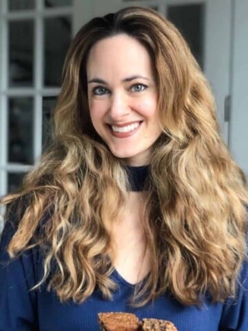 A woman with long hair and blue shirt smiling at the camera