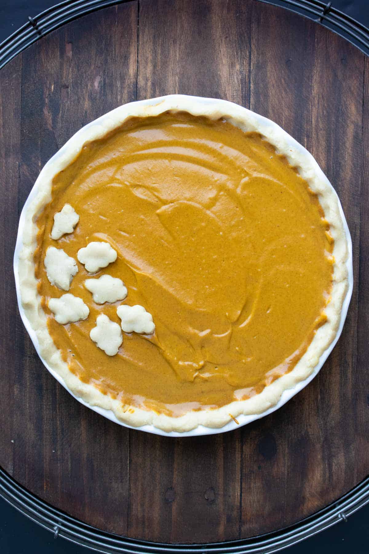 A raw pumpkin pie decorated with leaf shaped piece of crust.