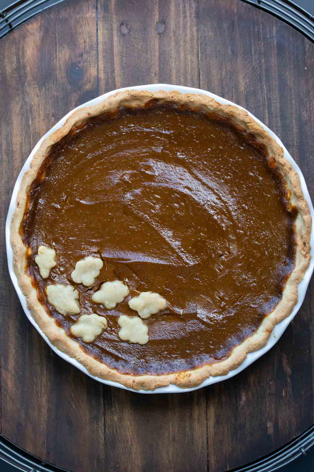 Top view of a baked pumpkin pie with crust leaves on the edge.