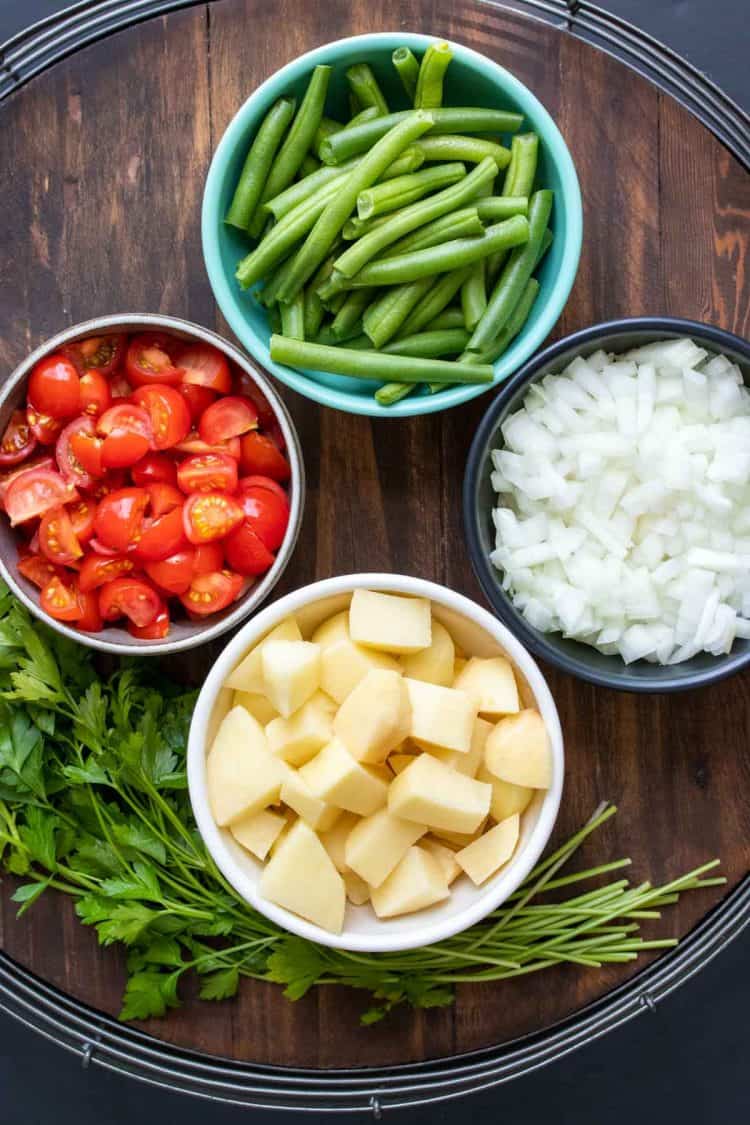 Bowls filled with veggies to make Greek green beans