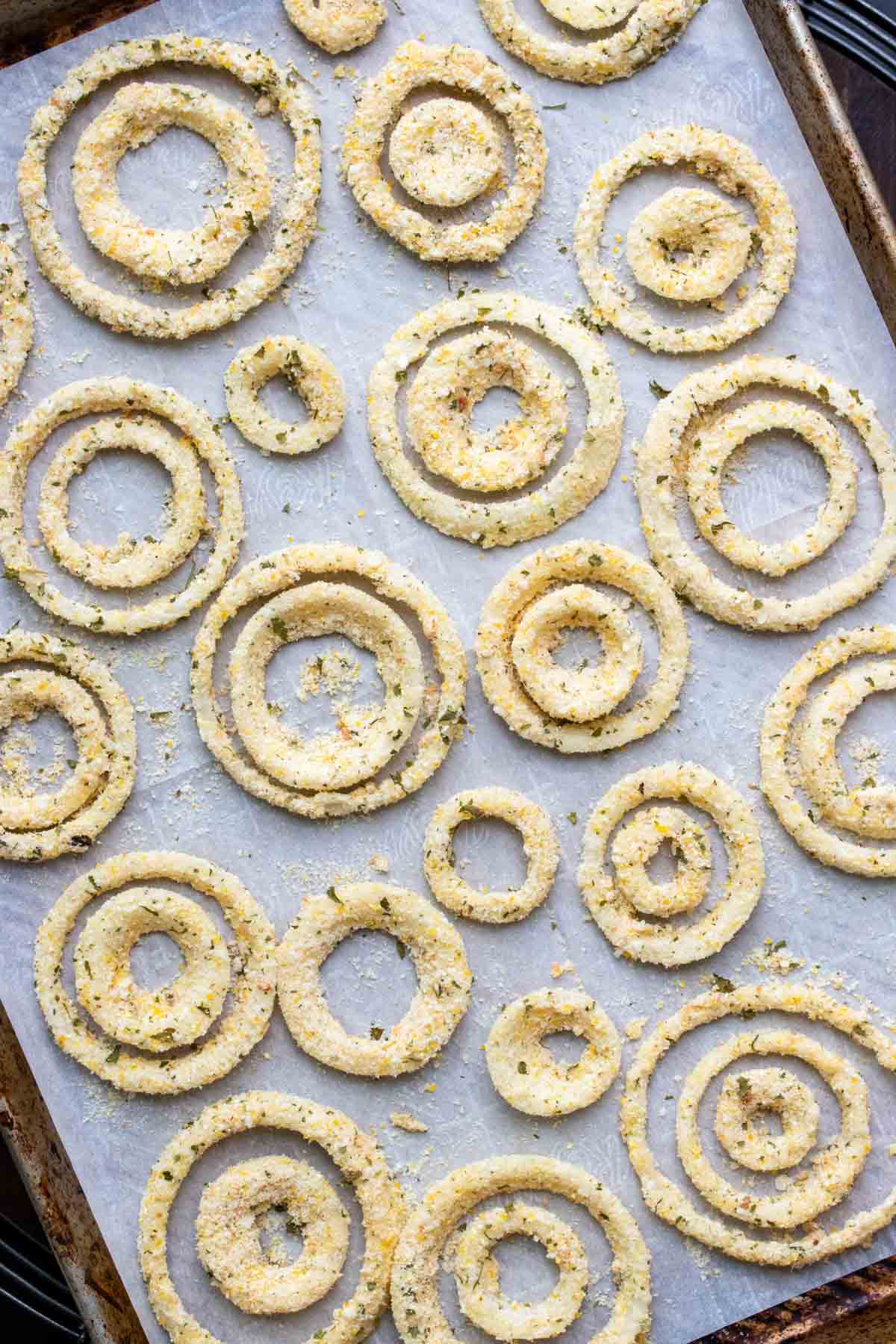 Crispy coated slices of onion on a parchment lined baking sheet