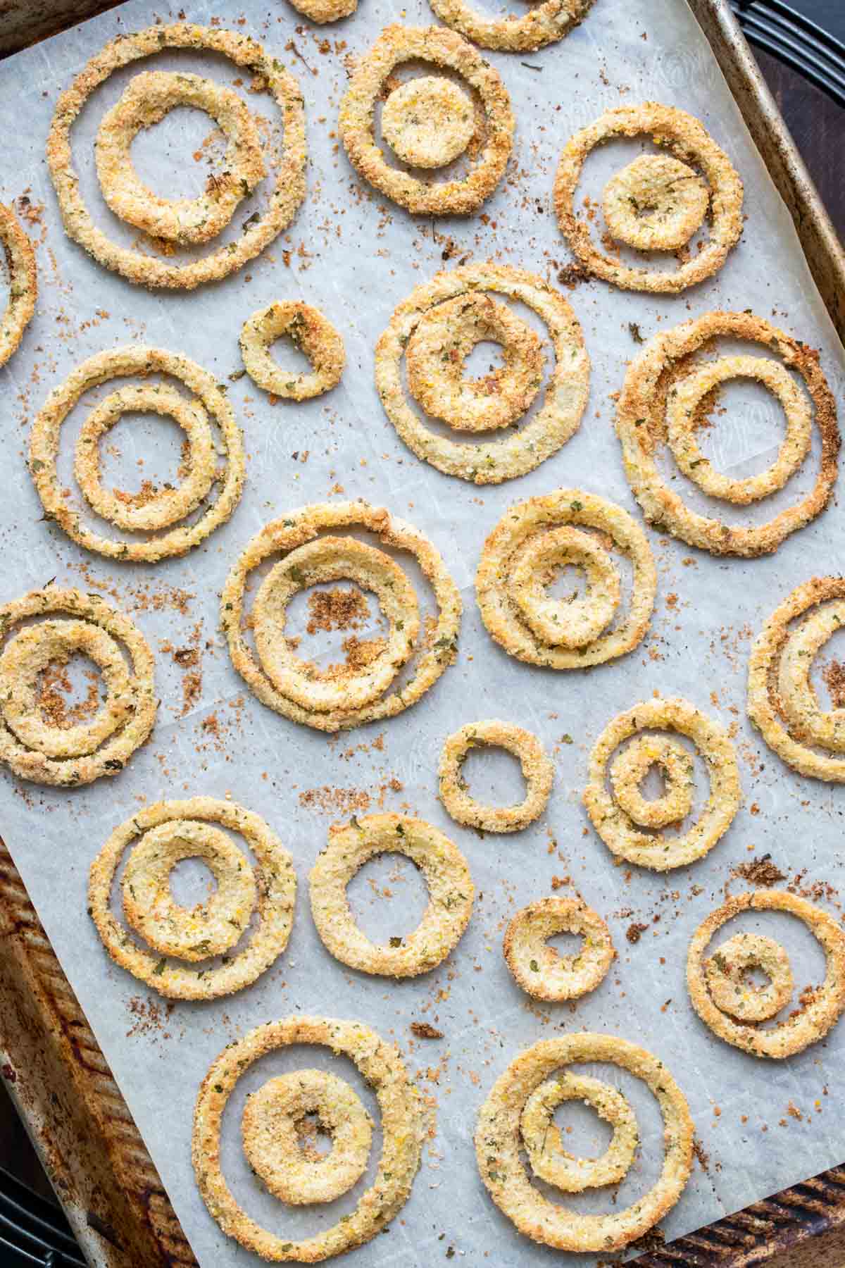 Baked onion rings on a piece of parchment on a baking sheet