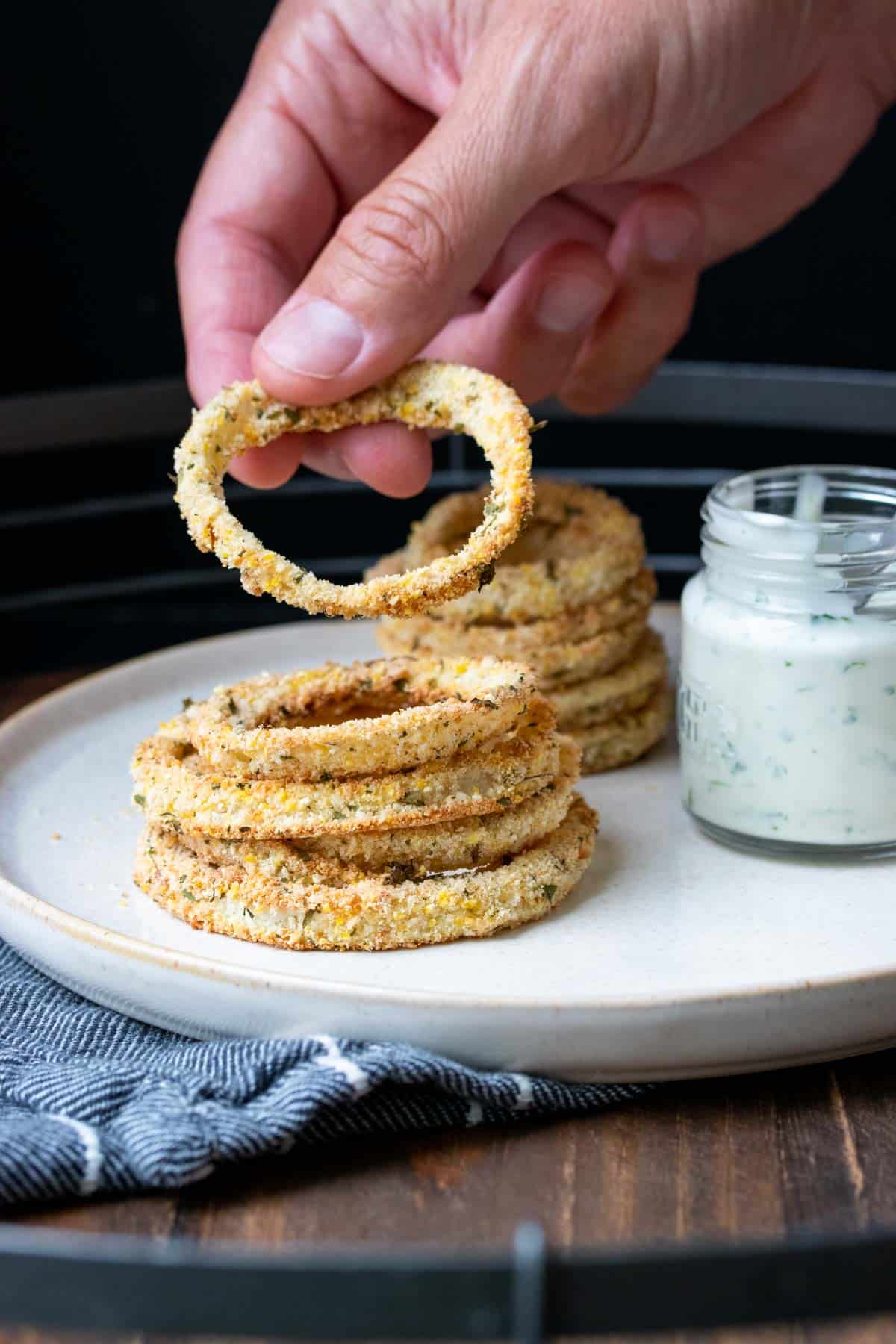 Hand picking up an onion ring from a pile of them