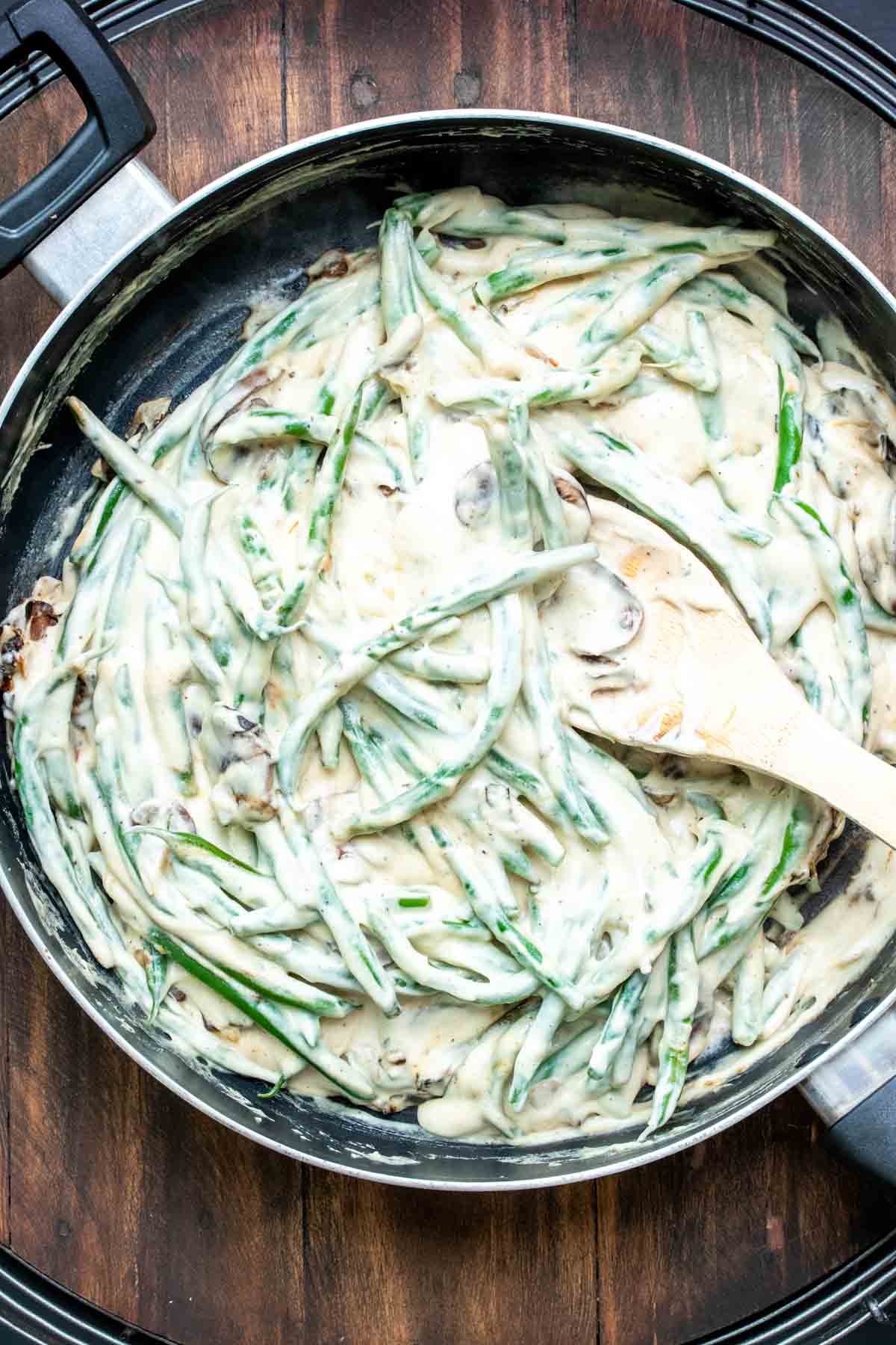 Green beans with creamy sauce being stirred in a pan