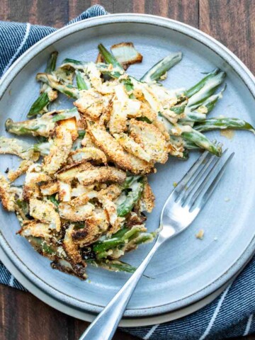 A grey plate with some green bean casserole and a fork on it.