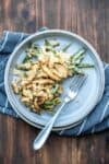 A serving of green bean casserole with fried onions on top on a grey plate with a fork in it.