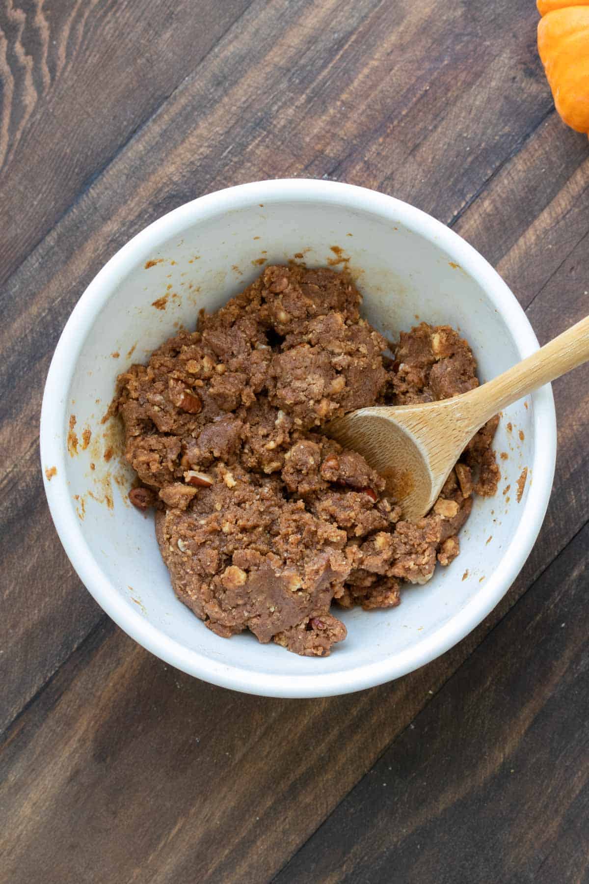 Spoon mixing dough for pumpkin energy balls in a white bowl