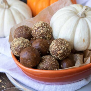 Orange bowl with a pile of pumpkin energy balls and some covered in graham crackers