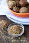 Pumpkin energy ball being rolled in crushed graham crackers in a glass bowl