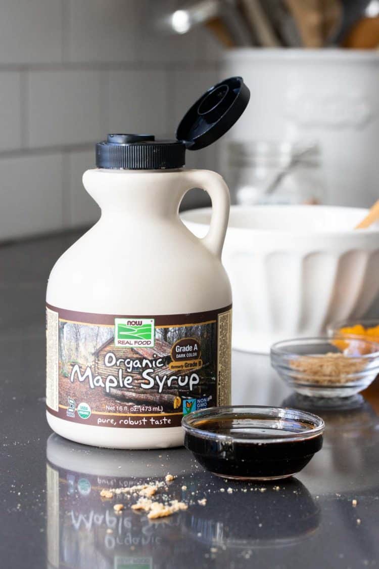 A cream colored container of maple syrup on a grey surface