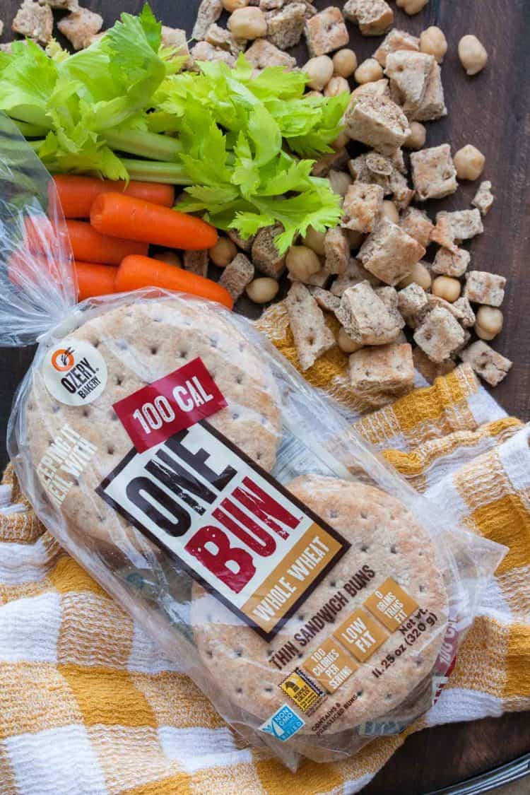 Package of bread surrounded by cubed bread pieces and chopped veggies