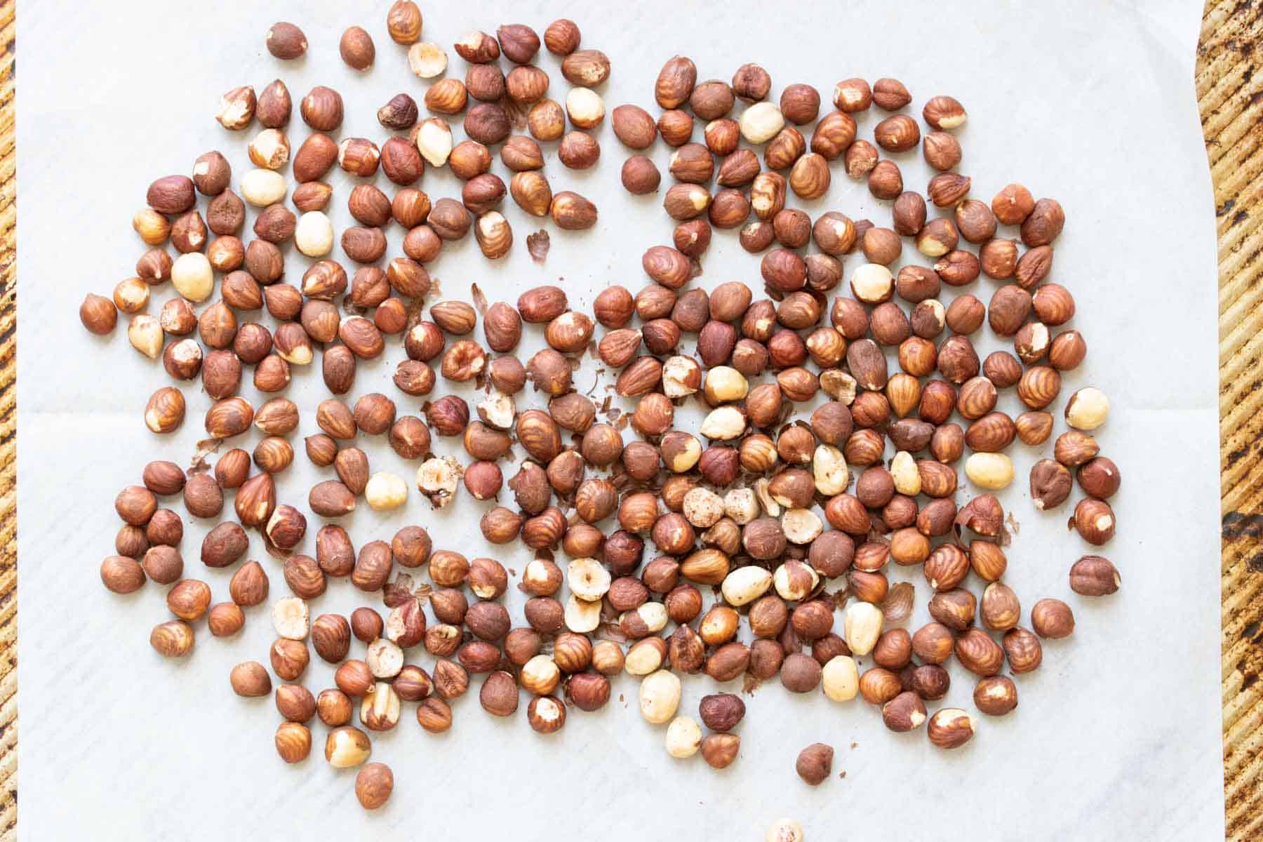 Hazelnuts on a piece of parchment paper that is on a cookie sheet