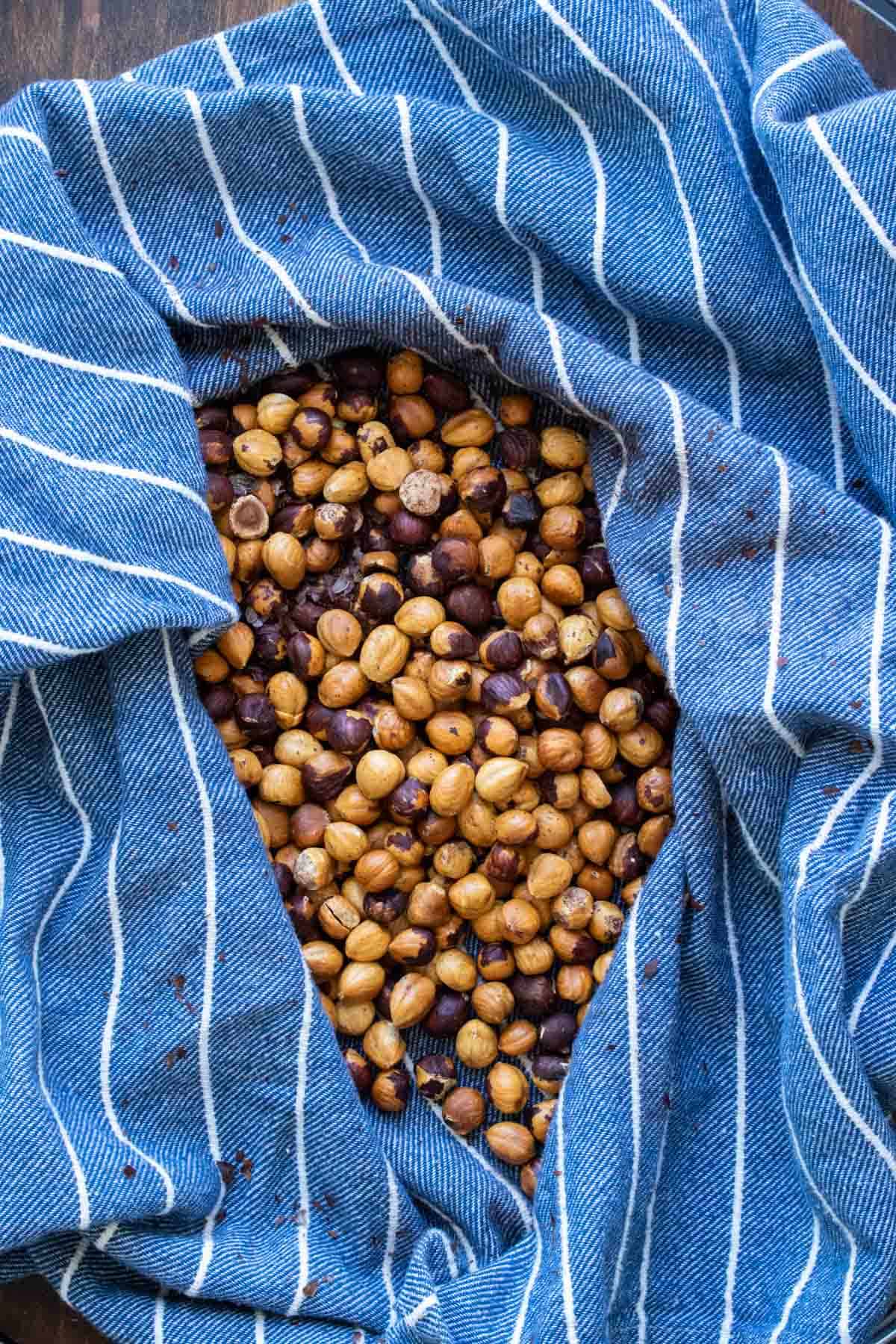 Dark blue kitchen towel filled with roasted hazelnuts