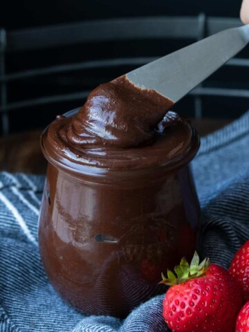 Someone getting a scoop of Nutella out of a glass jar