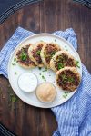 White plate with potato pancakes next to sour cream and applesauce