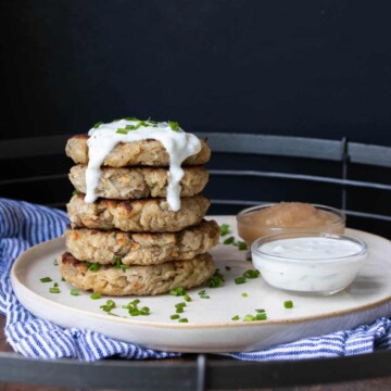 Stack of potato pancakes on a cream plate with dippers next to it