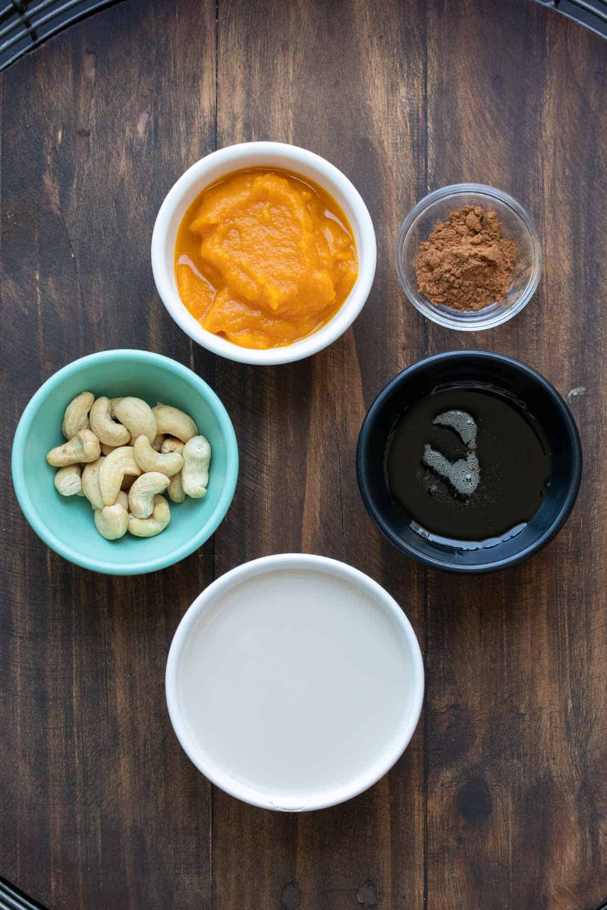 Different colored bowls with ingredients for a pumpkin pie smoothie