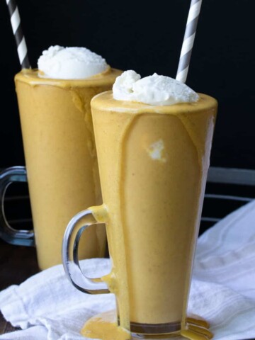 Two glass jars filled with pumpkin milkshakes and whipped cream