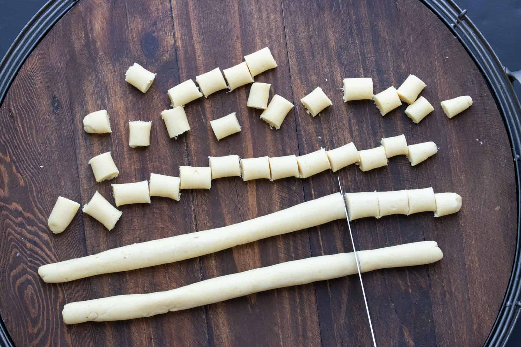 Rolled out dough pieces being cut into gnocchi.