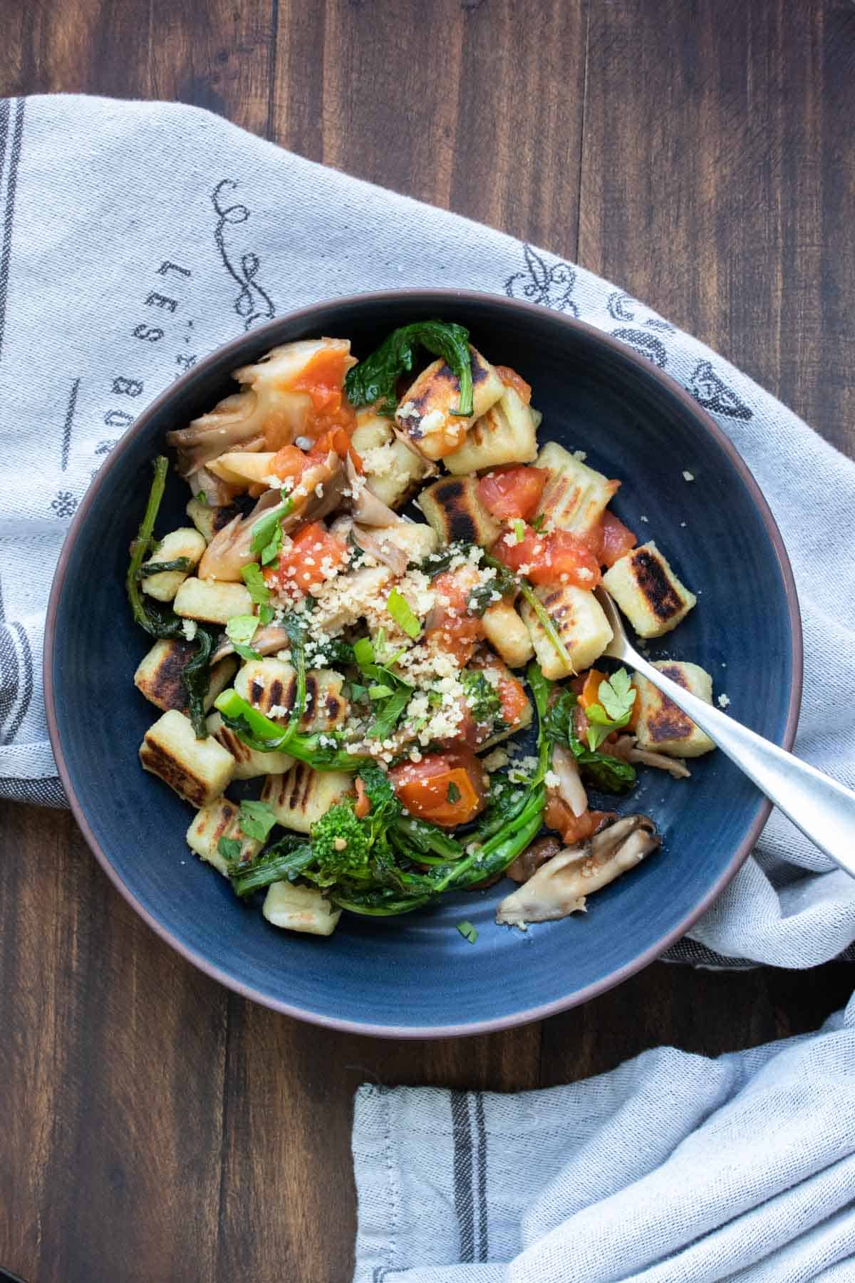 Bowl with cooked crisped gnocchi and fresh tomatoes