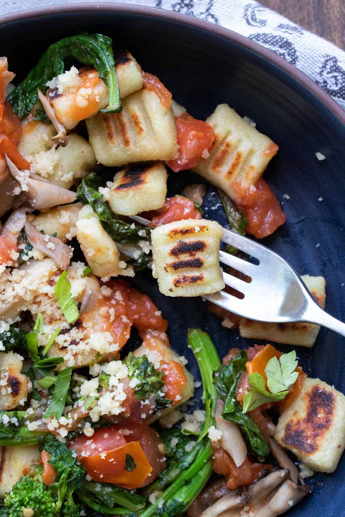 Fork getting a bite of gnocchi from a bowl
